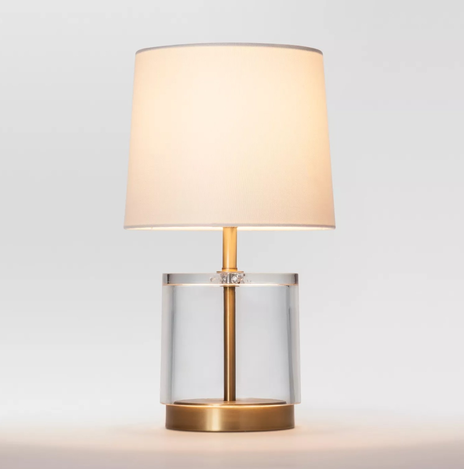 the lamp lit up with a brass base and glass fixture at the bottom