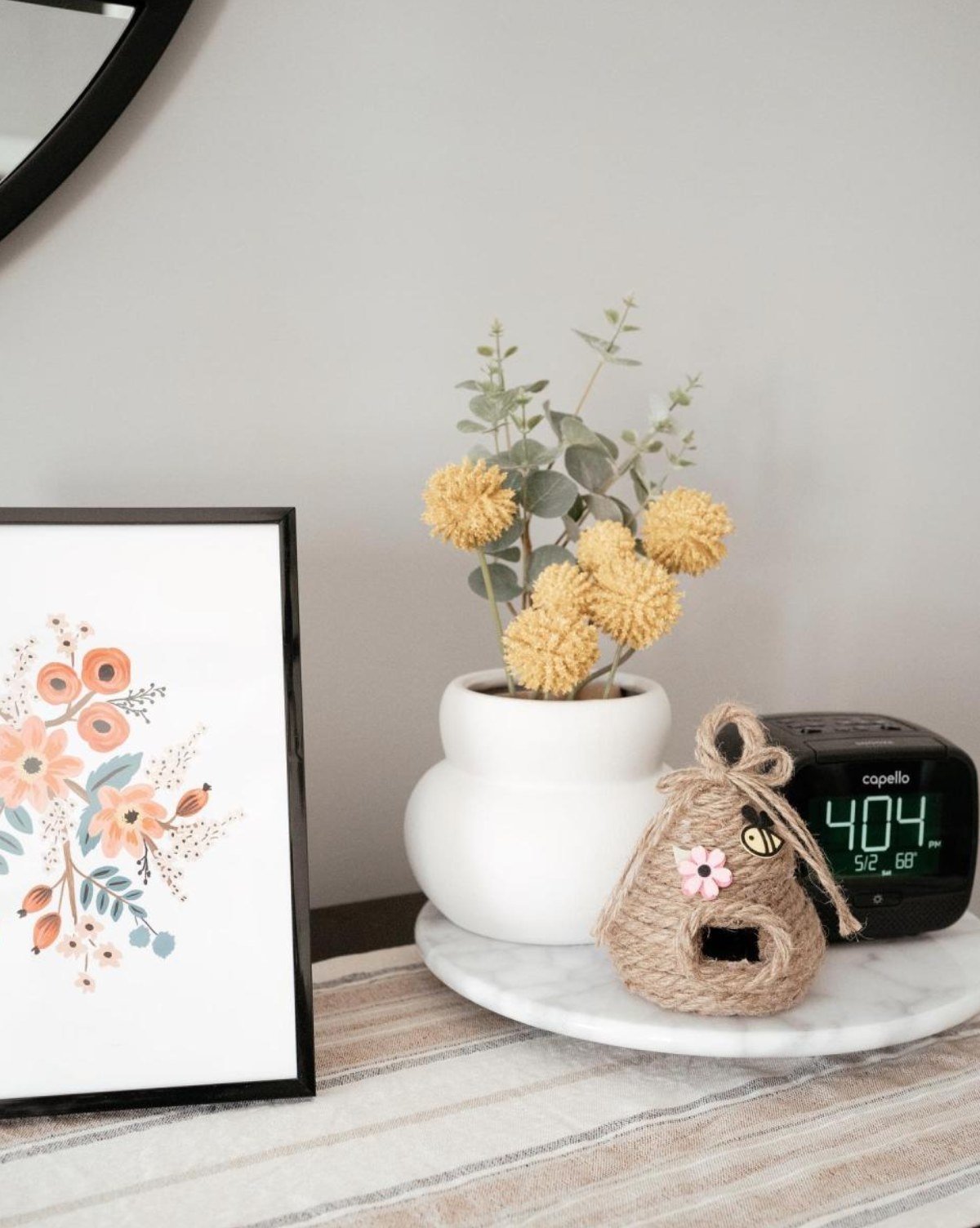 the vase with flowers in it next to an alarm clock and a picture frame
