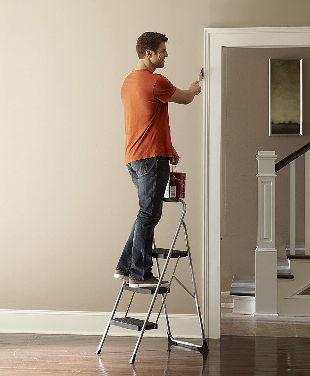 model using the step stool to paint a door trimming