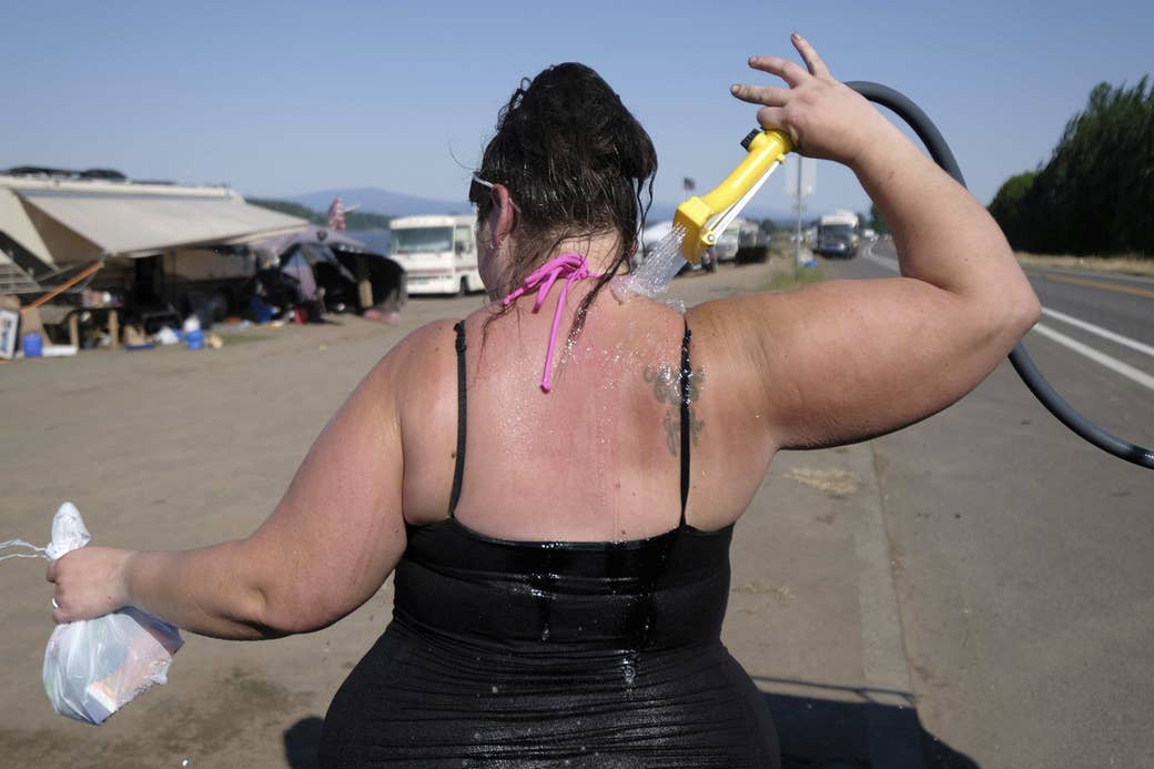 A woman in a tank top sprays herself down with a hose