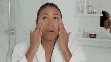 A woman applying her skincare products to her face