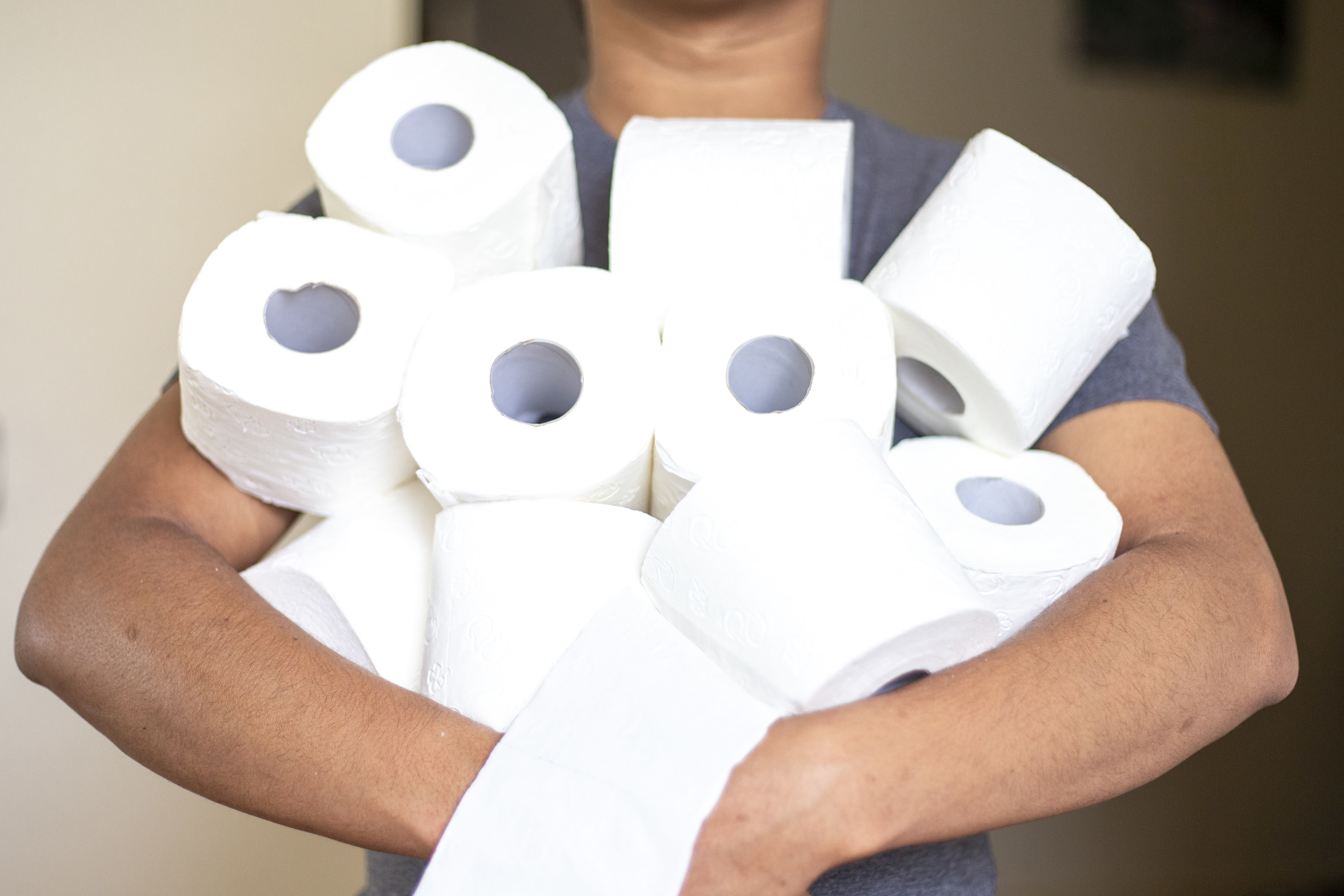 Person holding about 10 rolls of toilet paper in their arms