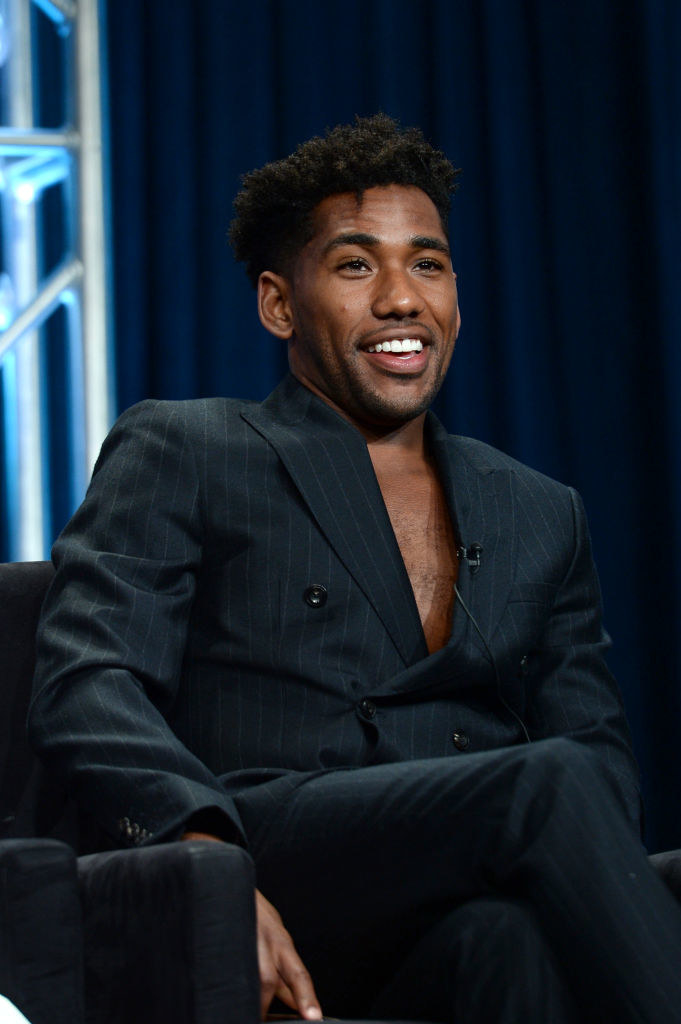 Brandon Mychal Smith wearing a suit and sitting at an event