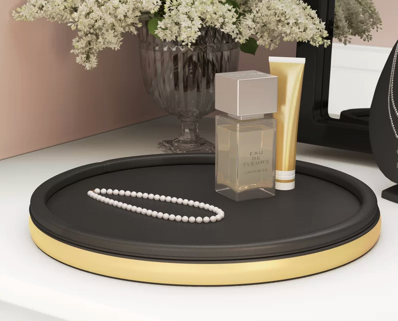 the brass and black round tray with a couple of beauty products and a necklace displayed on it