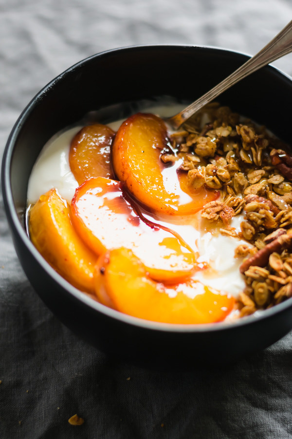 A bowl of yogurt with peaches and granola