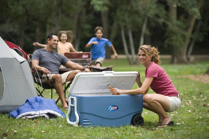 model grabbing a beverage out of the blue Coleman cooler