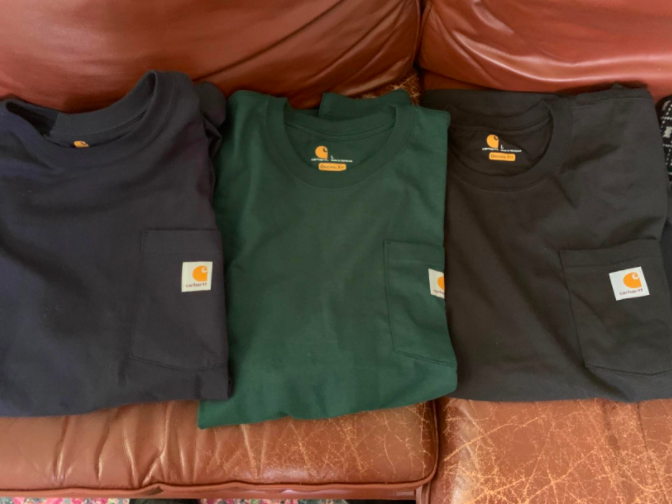 a reviewer photo of three of the shirts in blue, green, and black, with shirt pockets