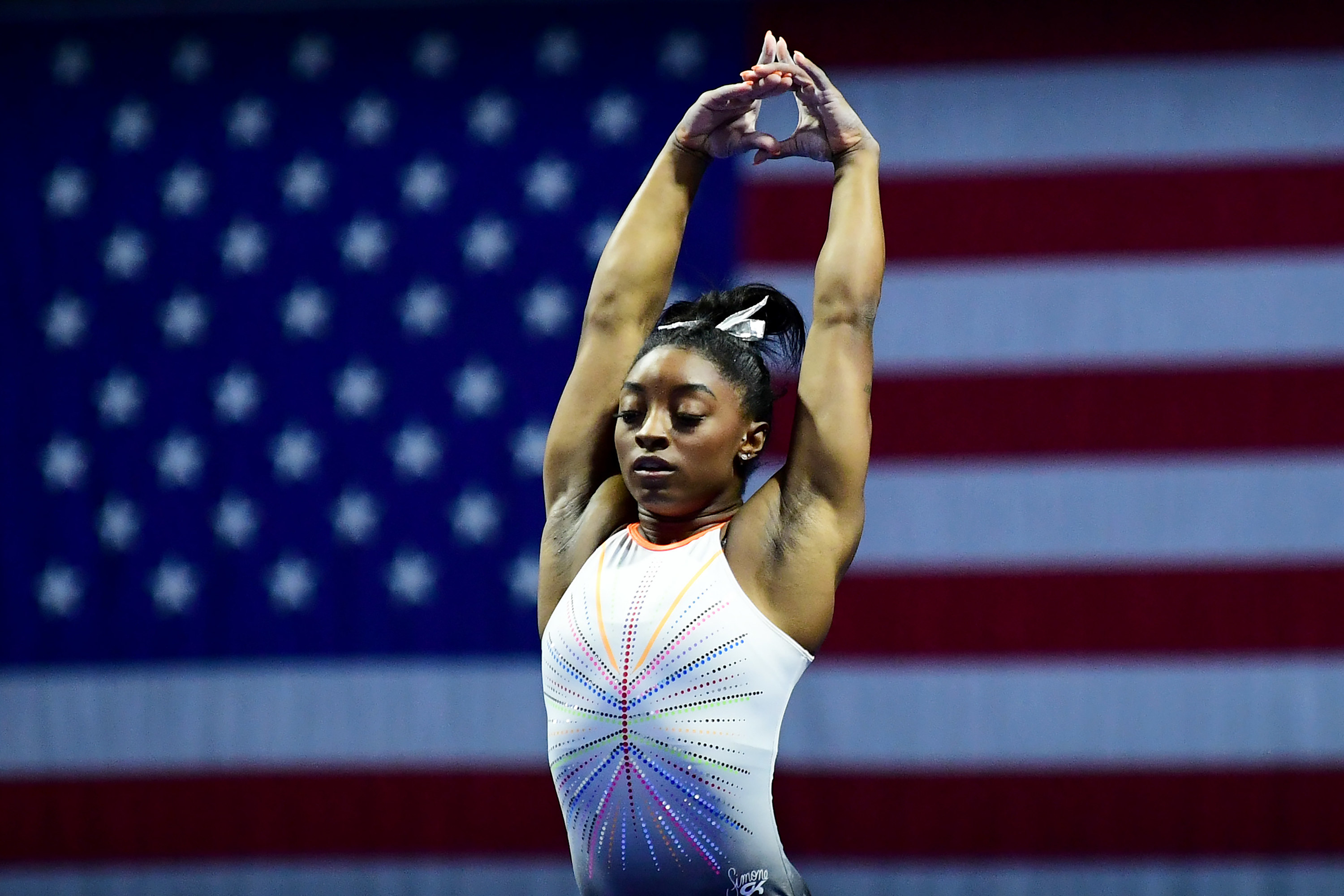 Simone Biles poses in front of the American flag