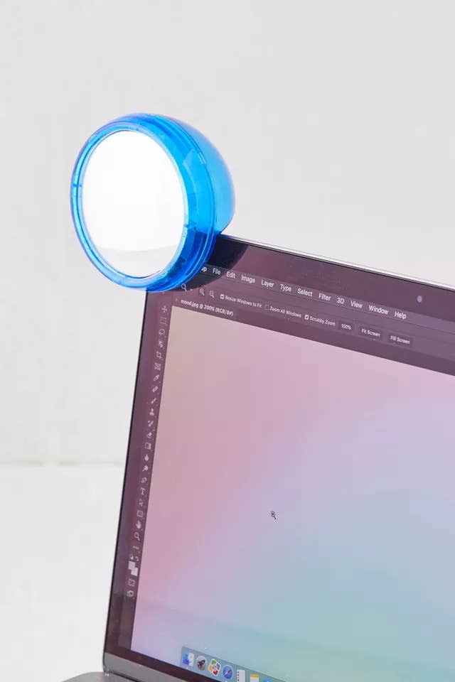 A small mirror clipped to the top of a laptop