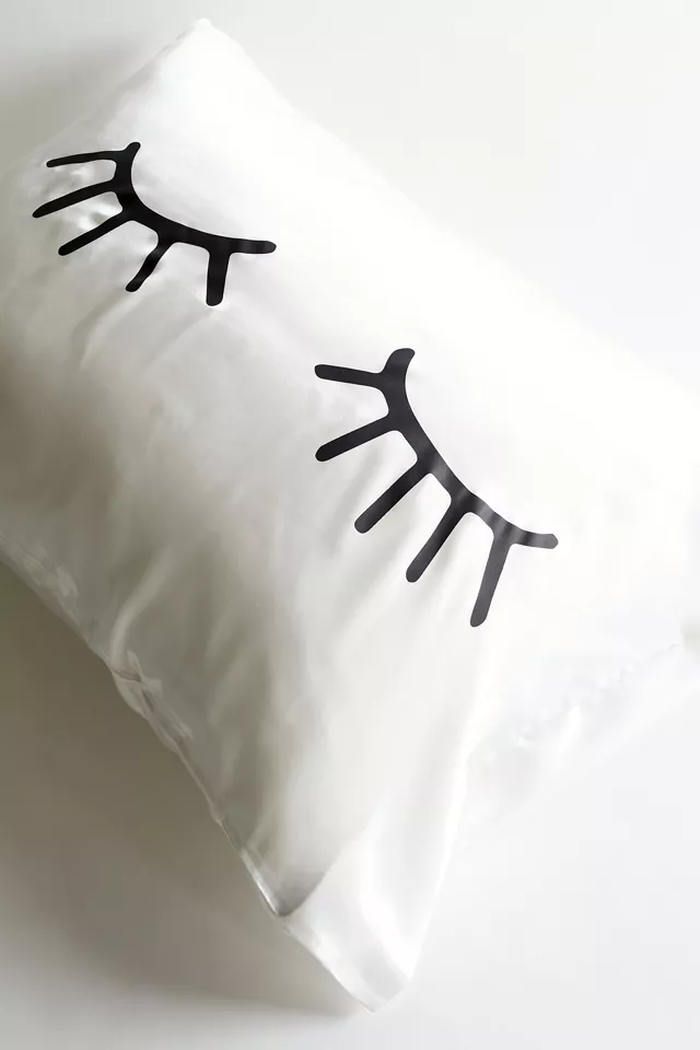 A satin pillowcase with a pair of eyelashes drawn on it