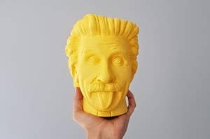 A hand holds a yellow 3D-printed head of Albert Einstein with his tongue out