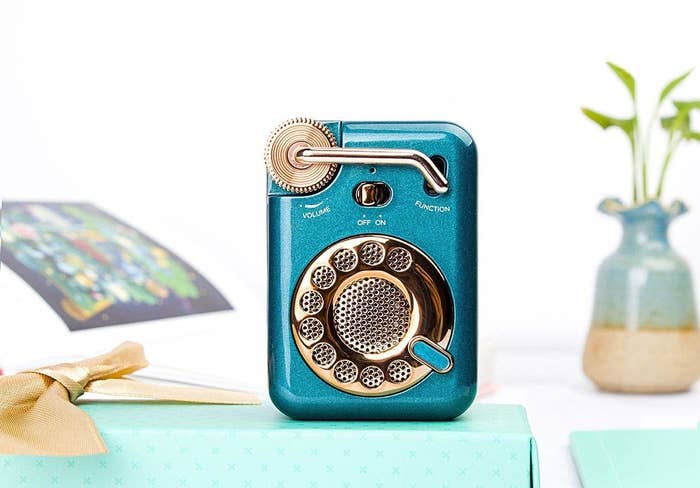 A retro style teal blue bluetooth speaker with golden coloured buttons