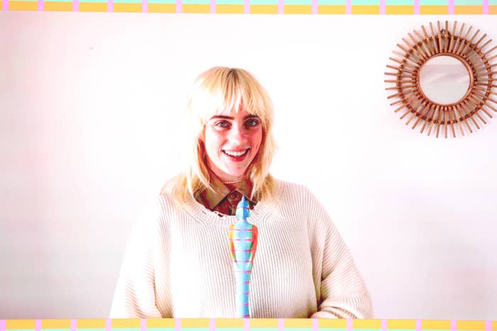Billie smiling and wearing a thick sweater while holding her Brit award