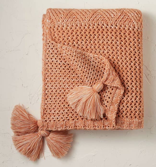 a terracotta throw blanket with tassles