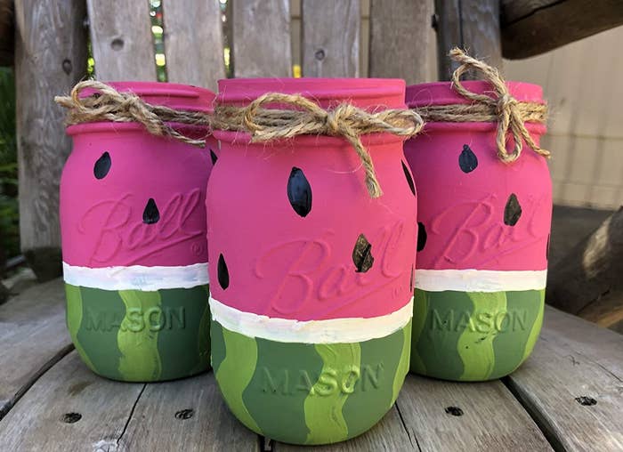 mason jars painted like the outside of a watermelon on one half and the inside of a red watermelon on the other half