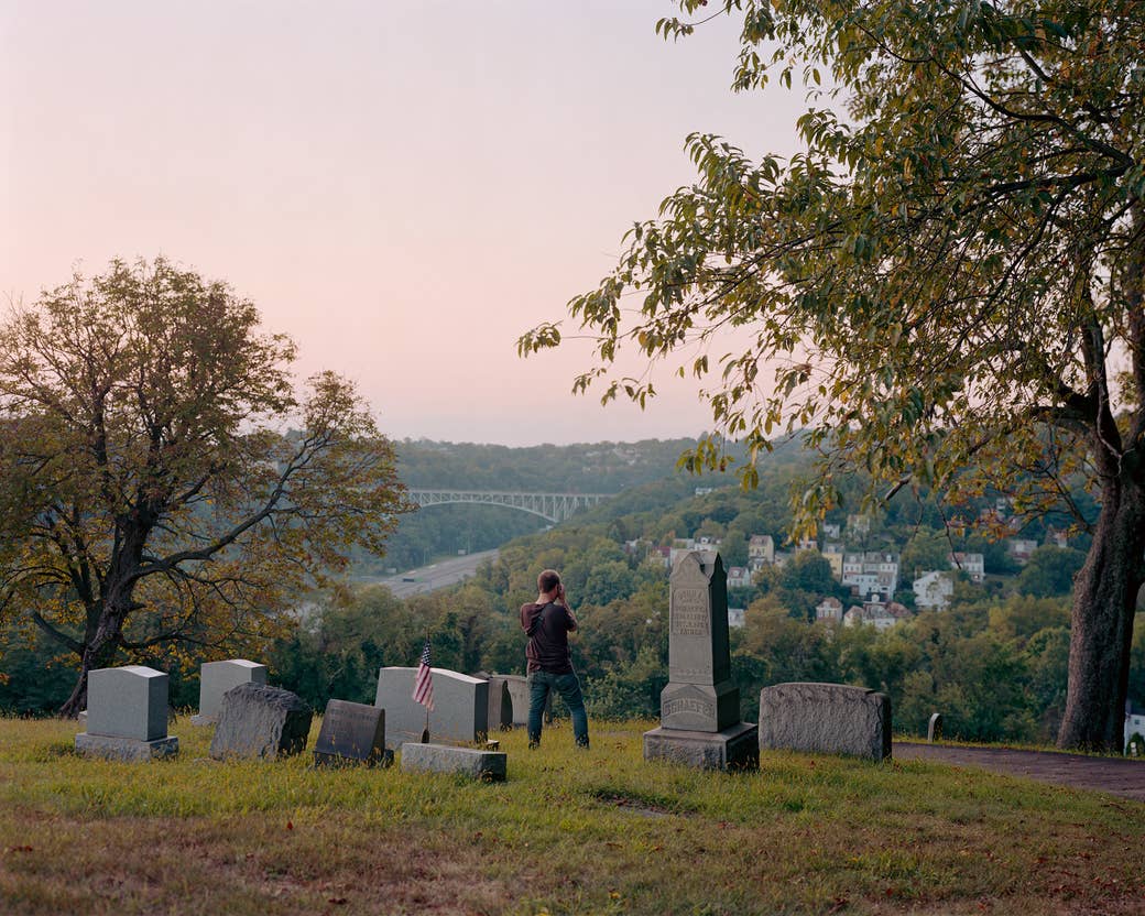 A man takes a picture in a graveyard, photographed from behind