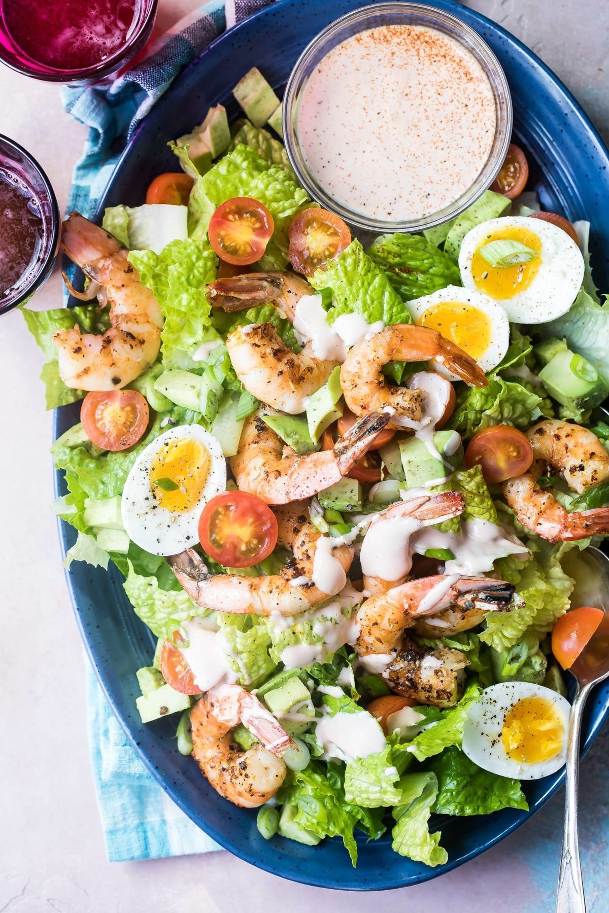 Shrimp Louie salad with hard boiled egg, tomato, lettuce, and dressing.