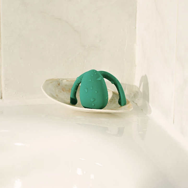 Green egg-shaped vibrator on side of bathtub