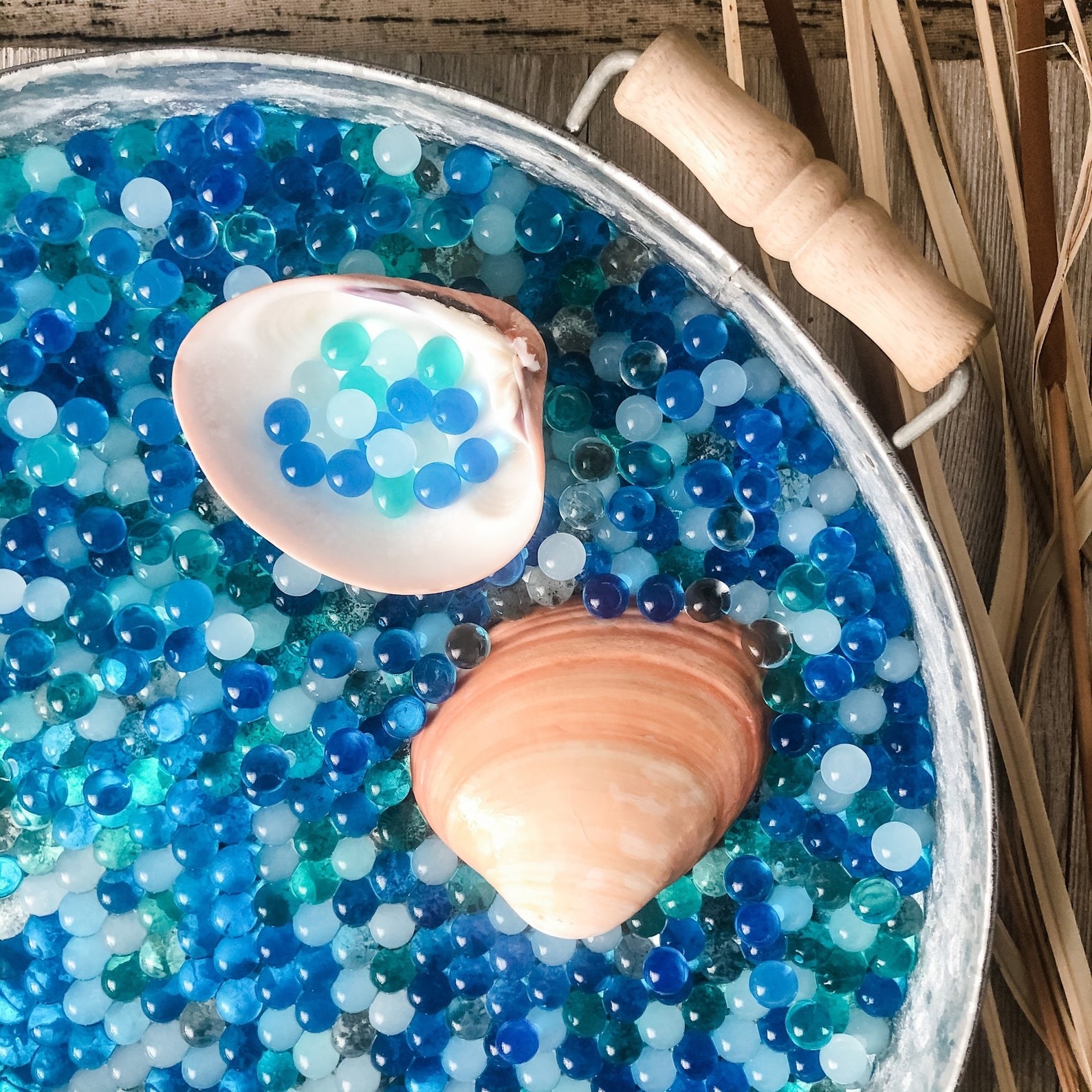Blue, teal, clear, and white water beads with a clam shell scoop