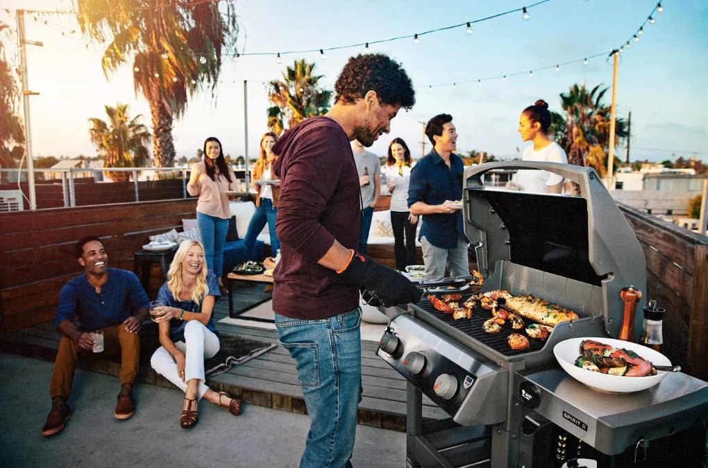 A model using a black/gray gas grill on a patio
