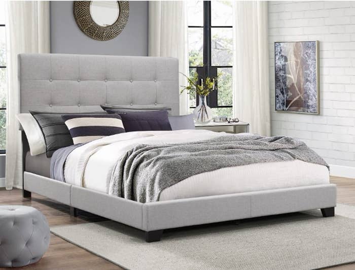 light grey upholstered bed with headboard and linens