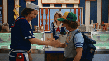 Steve and Dustin from Stranger Things play sword fight with each other in an ice cream shop