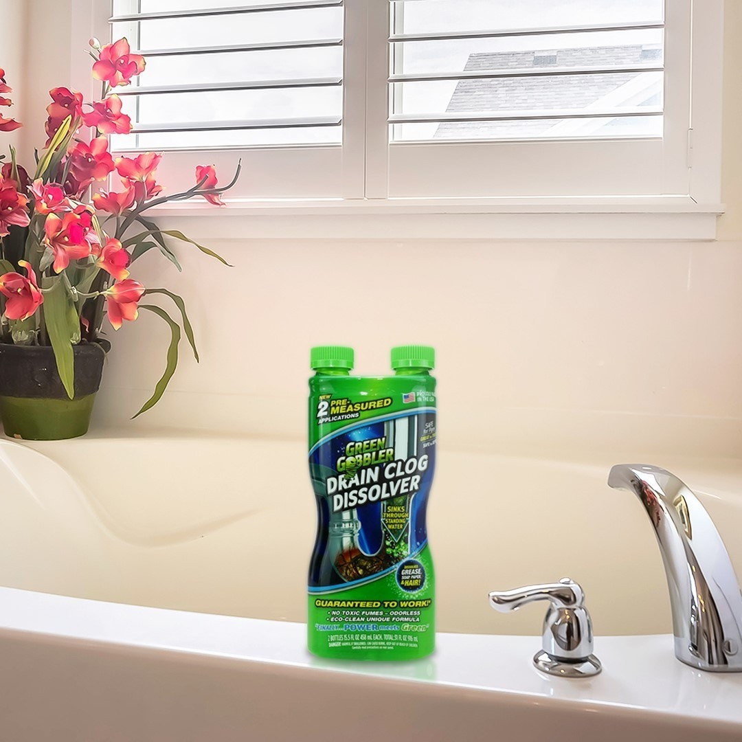 A bottle of the drain cleaner perched on the edge of a tub
