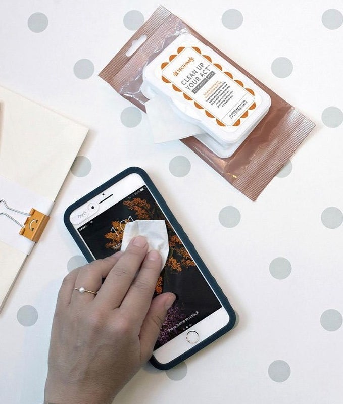 A person using one of the tech wipes to clean the screen on their phone