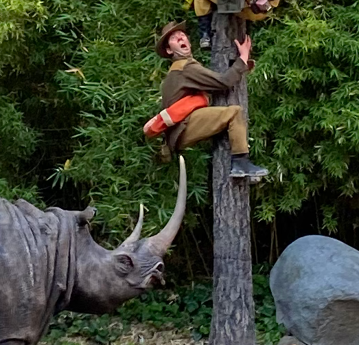 A man with a life vest around his waist, about to get poked by a rhino