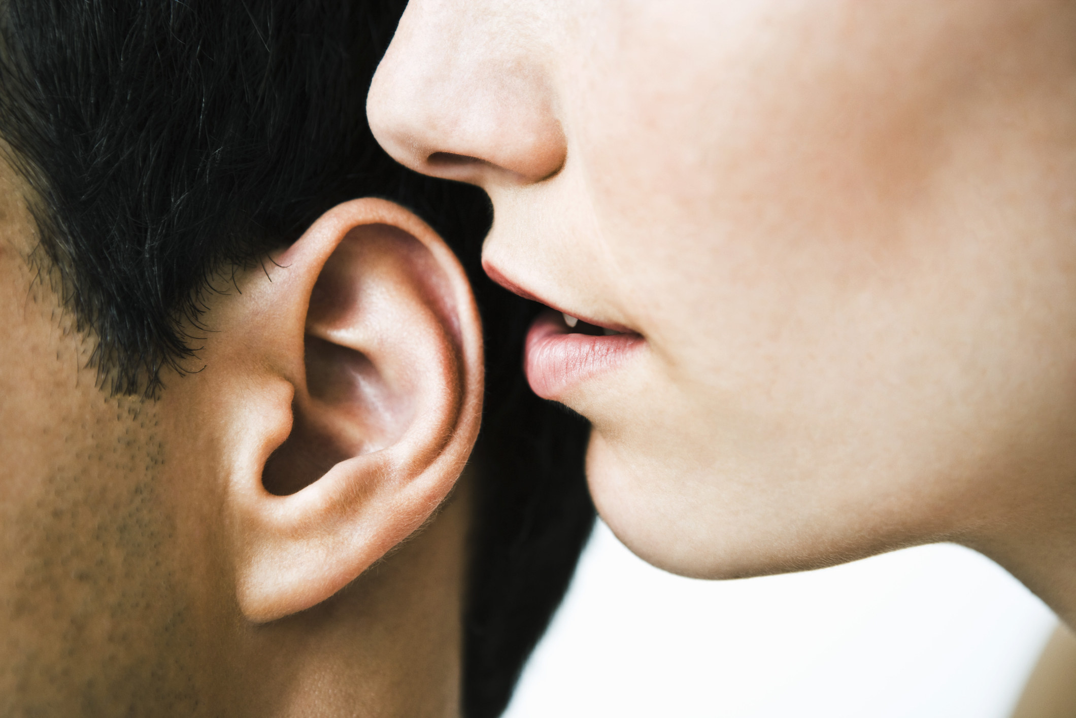 a person whispering into her partner&#x27;s ear
