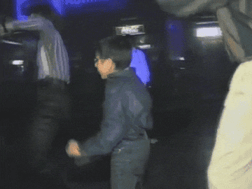 A kid with glasses dances in a club.