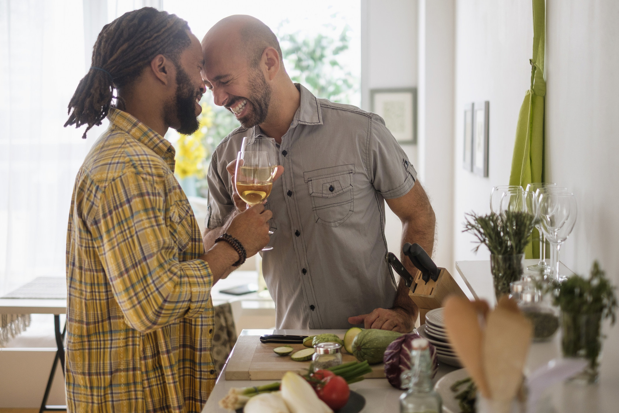 Gay couple laughing over wine in the kitchen