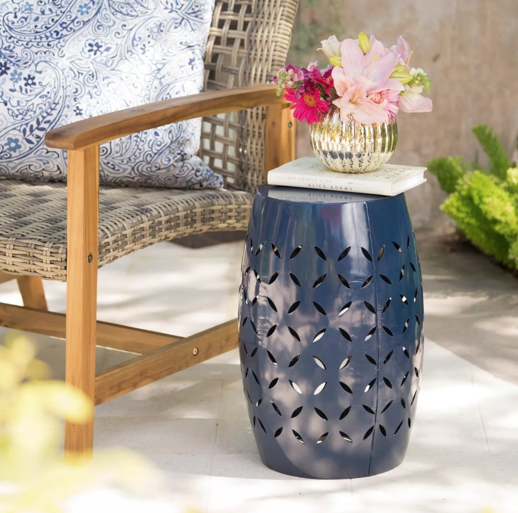 An iron side table in dark blue displayed on a patio