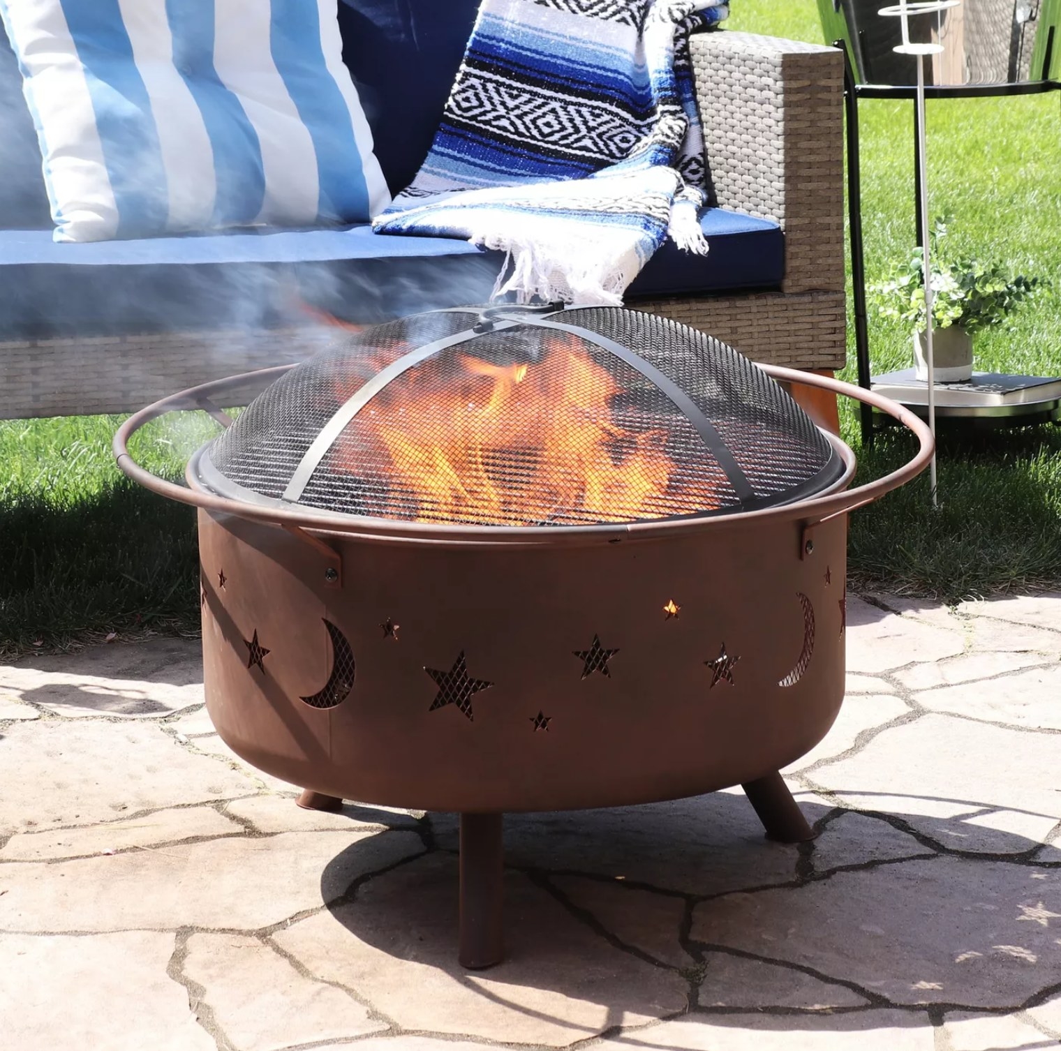 the metal fire pit with moon and star cutouts with a metal grate on top