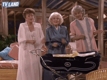 Three of the golden girls dancing next to a baby carriage.