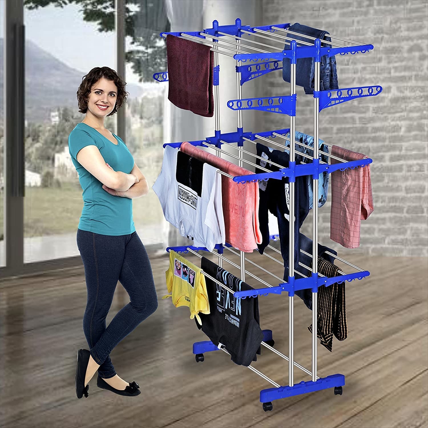 A woman in a room, standing next to a clothes drying stand with clean laundry on it