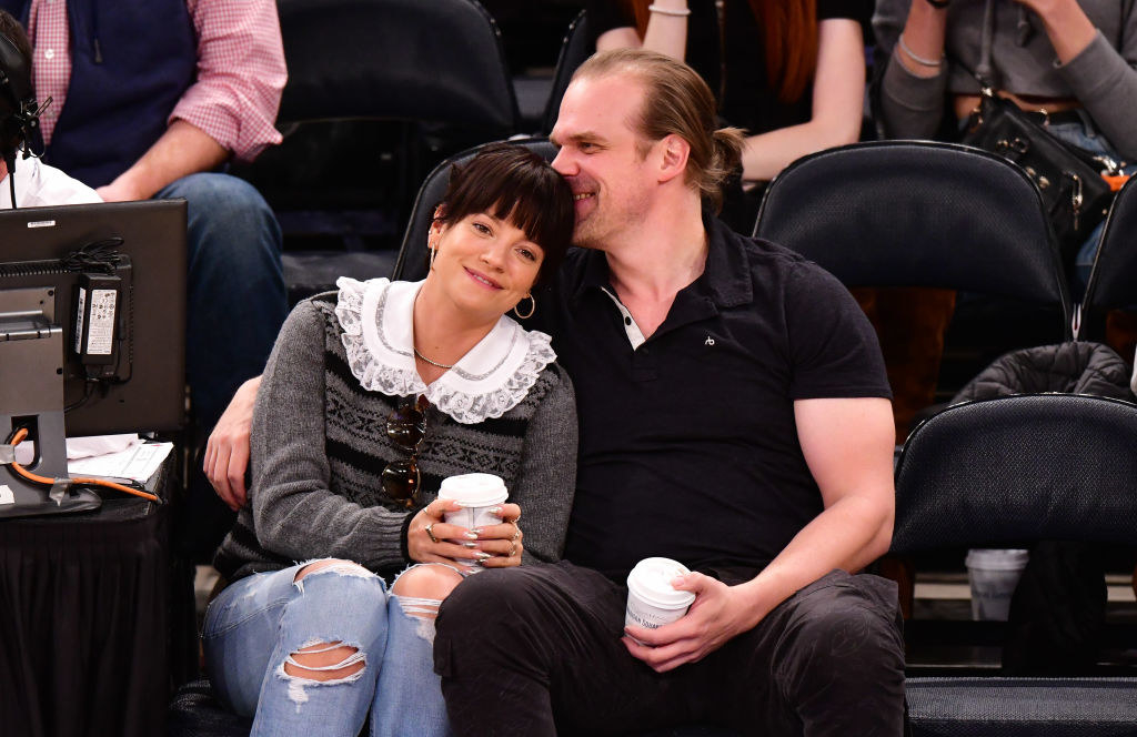 Lily Allen (L) and David Harbour cuddle at the New York Knicks v New Orleans Pelicans preseason game