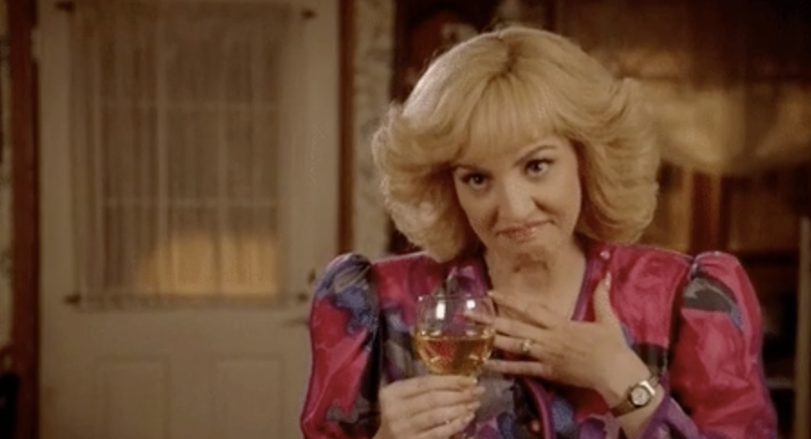 Beverly Goldberg holding wine and covering her heart