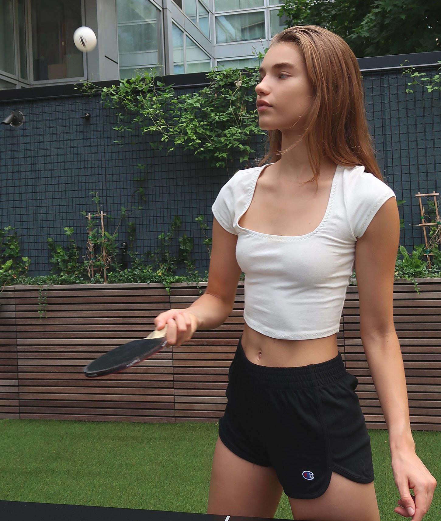 A person wearing the shorts with a cropped tee while playing ping pong