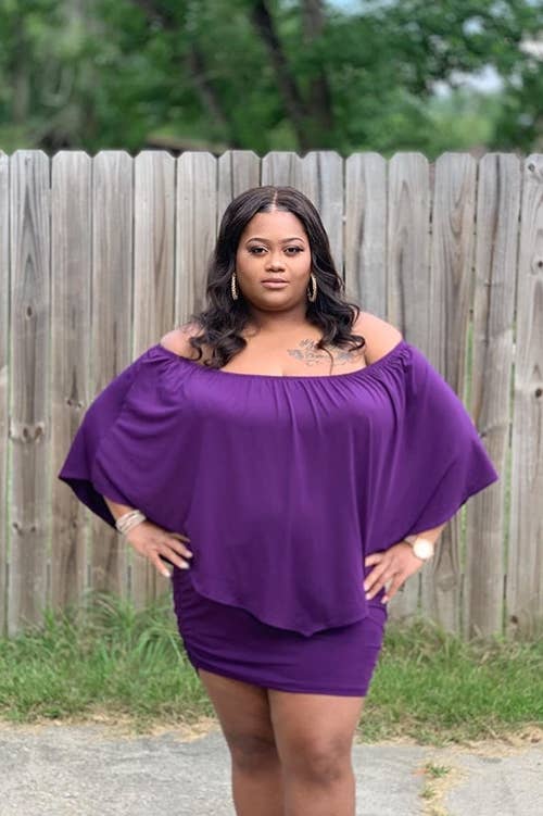 Reviewer wearing purple dress with the sleeves set as an off the shoulder dress