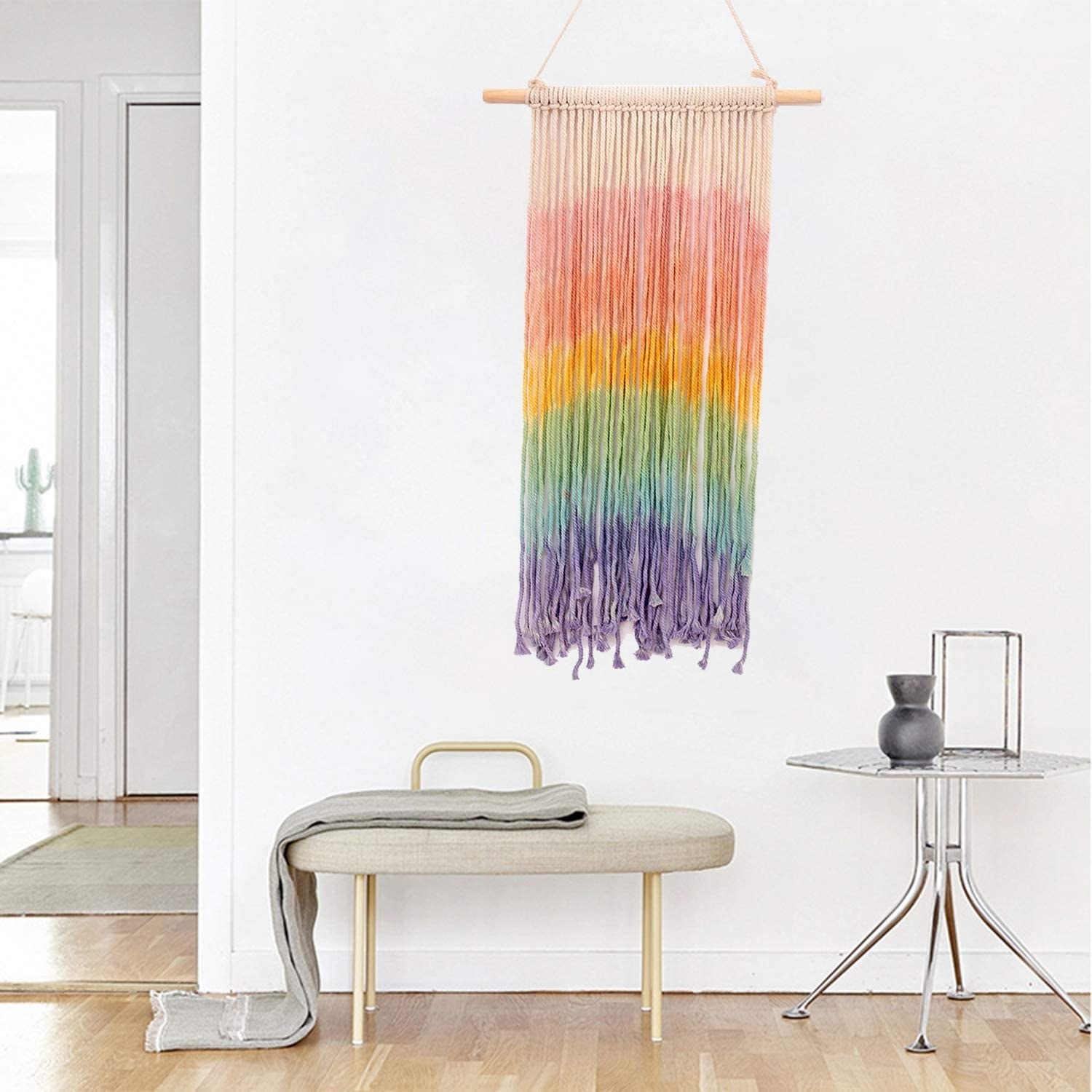 The rainbow colored macrame hanging on a while wall