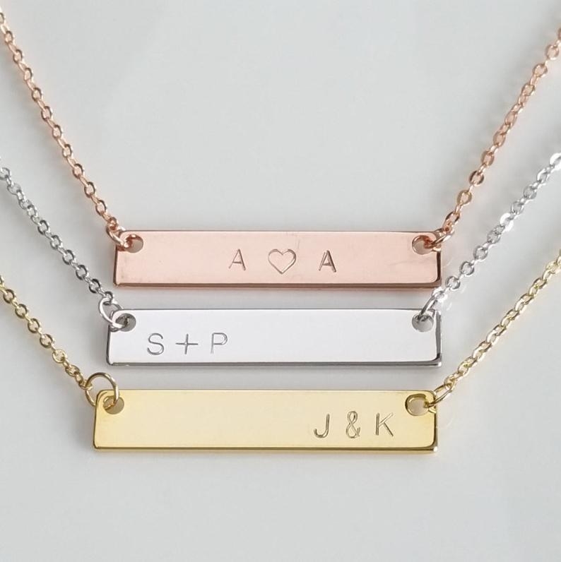 Three necklaces in different finishes with a gold horizontal bar that has initials on it