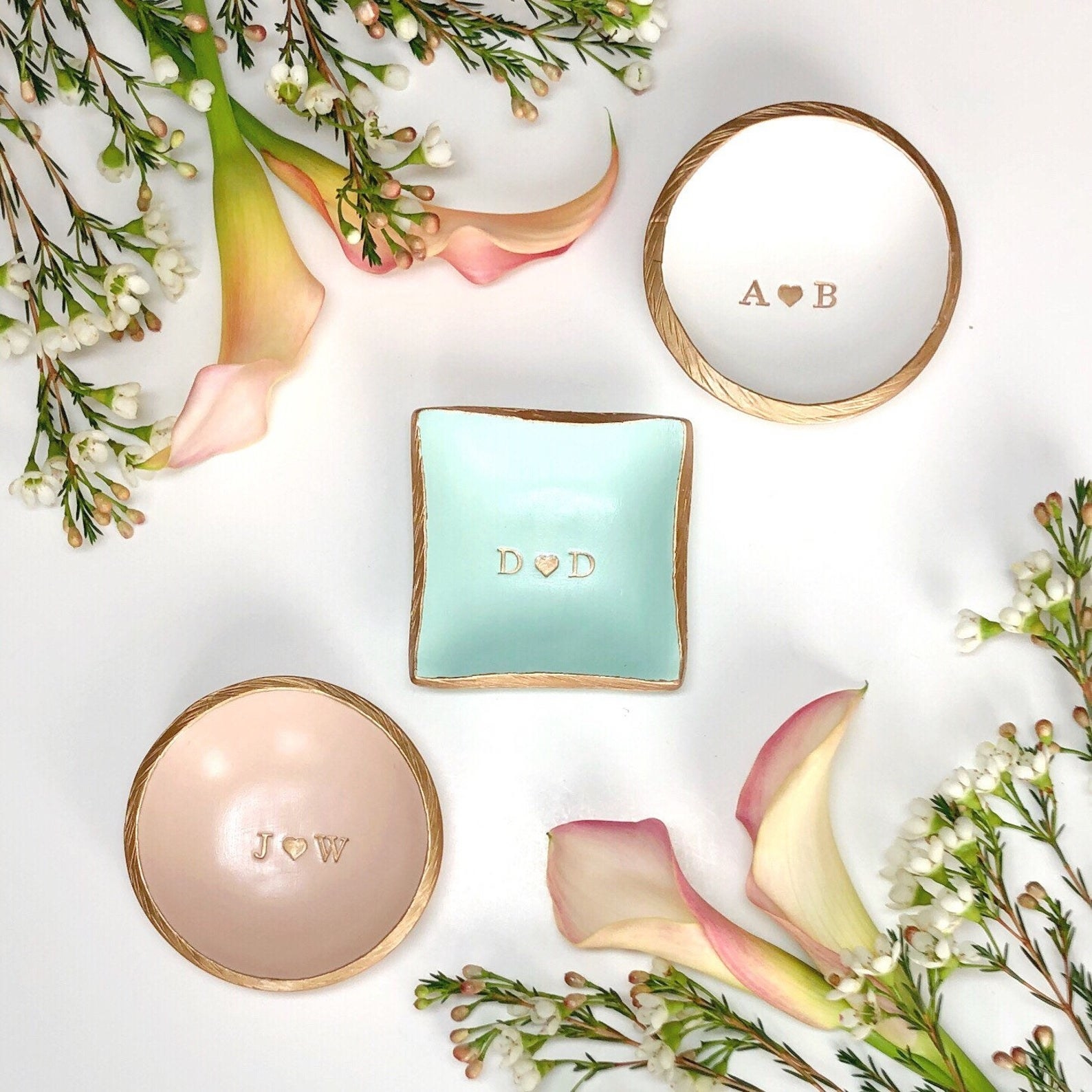 Three jewelry dishes in circle and square shapes and in pink, blue, and white