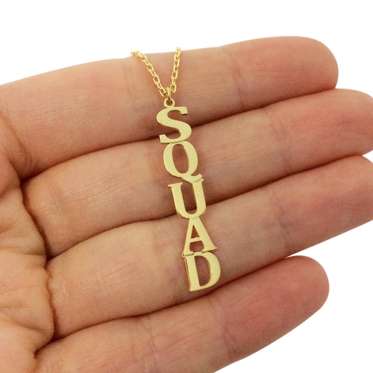 A gold necklace with a vertical name pendant