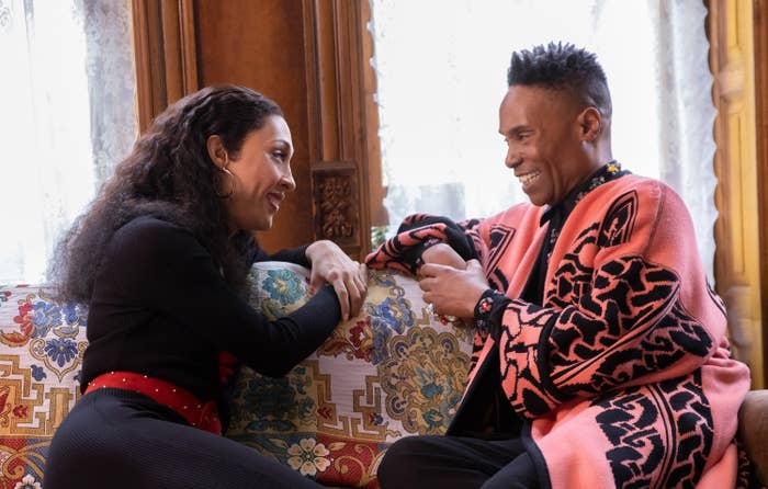 MJ and Billy sitting on a couch and smiling during a scene from pose