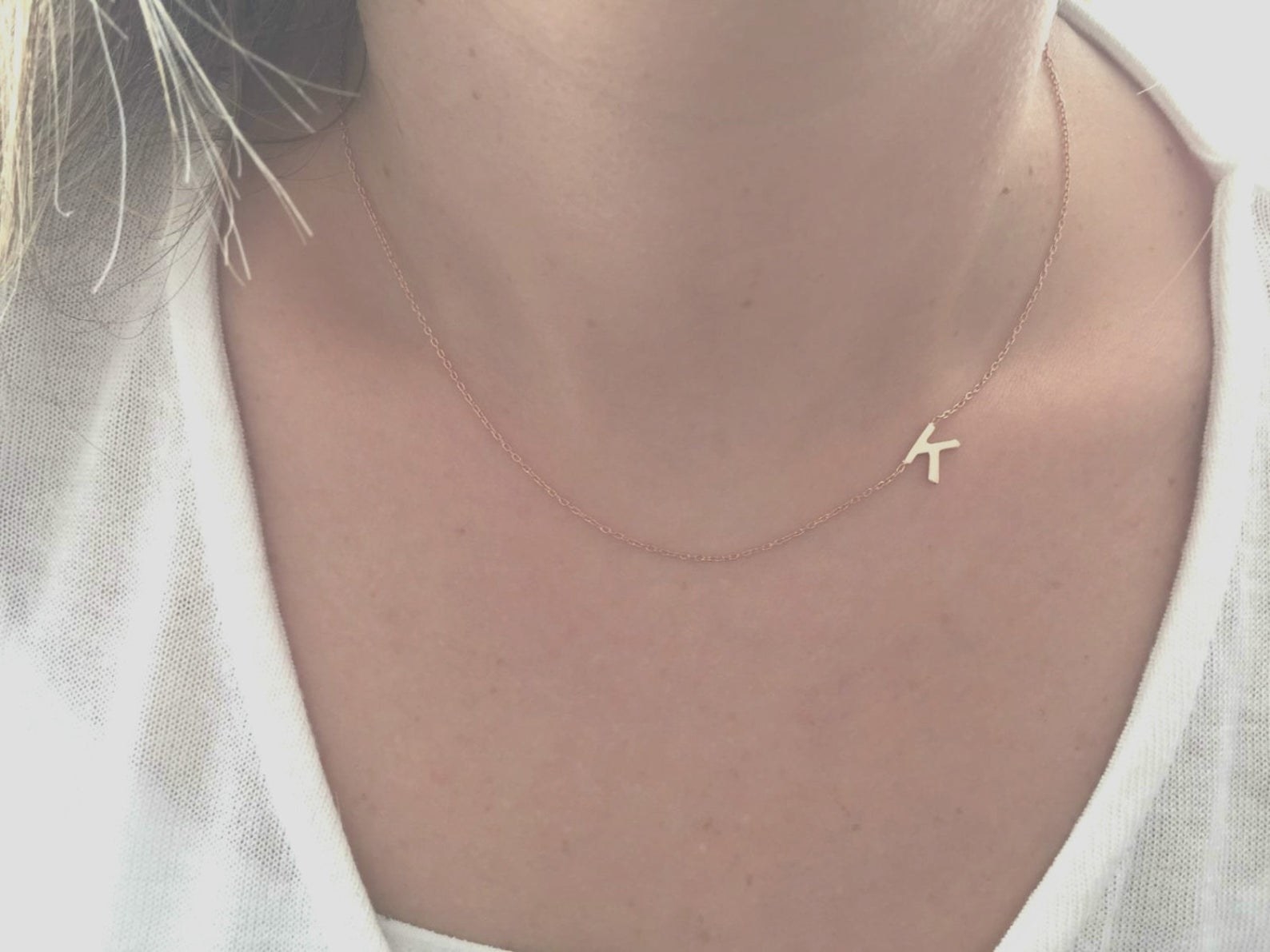 Model is wearing a dainty necklace with the letter K on it