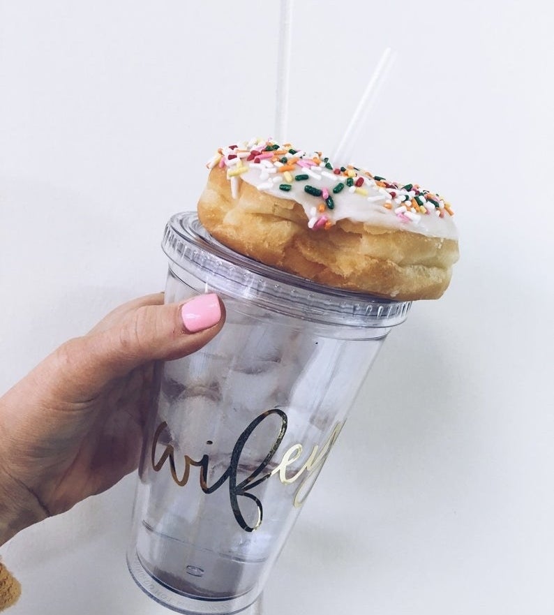 Model is holding a clear acrylic tumbler with the word &quot;wifey&quot; written in gold and donut on top