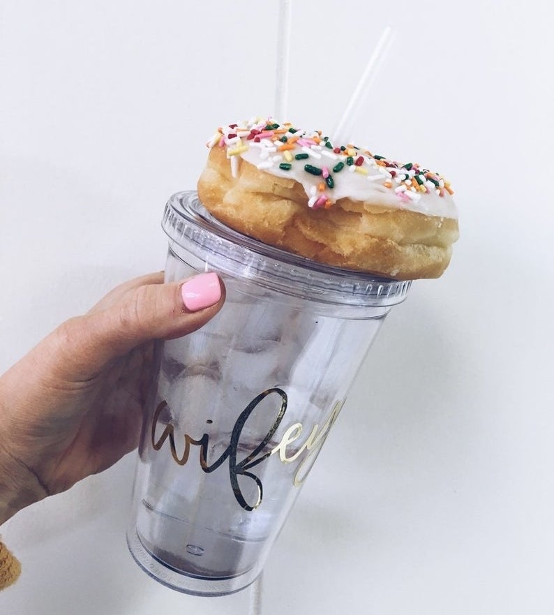 Model is holding a clear acrylic tumbler with the word &quot;wifey&quot; written in gold and donut on top