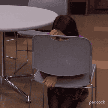 April Ludgate hiding behind a chair in shame