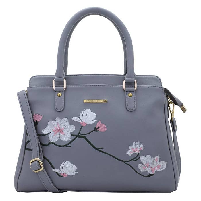 A grey leather bag with a pretty white and pink floral design embroidered on it
